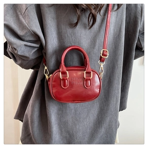 Detailed close-up of dark red mini crossbody bag with embossed logo and round handle