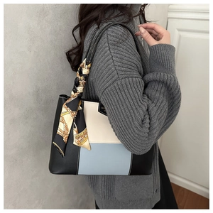 Detail of color-block tote bag with decorative silk scarf handle on model shoulder