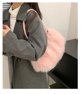 Detail of pink plush shoulder bag with soft faux fur texture shown on a grey coat
