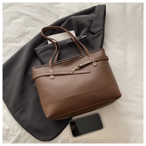 Detail of lychee texture brown leather tote bag with metal buckle and fashion logo