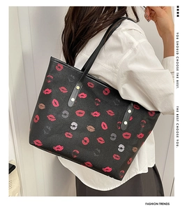 Detail of black tote bag with red lip print pattern and gold rivet strap reinforcement