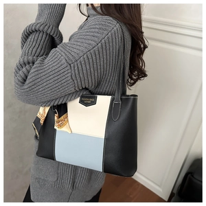 Detailed view of color-block tote bag with decorative scarf on a stylish shoulder strap
