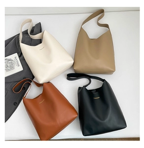 Quatre sacs cabas minimalistes en crème, kaki, marron et noir présentés à plat avec style