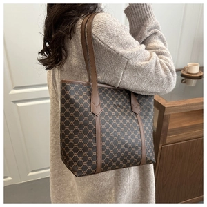 Side view of a vintage monogram tote bag with brown leather trim on a female model