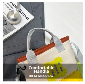 Detail of oxford fabric travel bag featuring orange piping and gray woven handles