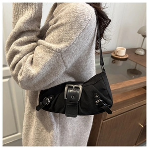 Close-up of black retro shoulder bag with silver belt buckle details on canvas fabric