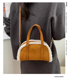 Detail of crossbody ginger suede bag with white faux shearling trim on grey sweater