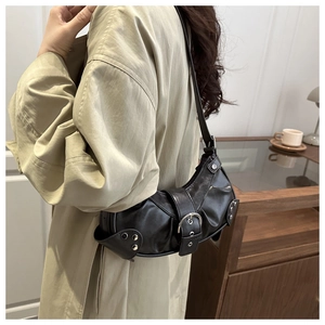 Close-up of black retro shoulder bag with silver studs and buckles on model