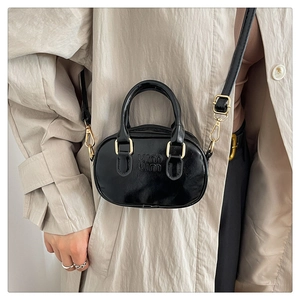 Detailed view of black glossy leather mini bag with embossed logo and adjustable strap