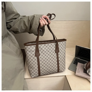 Macro shot of retro patterned tote bag with brown leather handles and chic office props