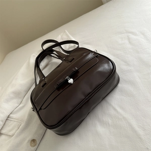 Chocolate brown faux leather Boston bag with bow and silver heart charm on white fabric