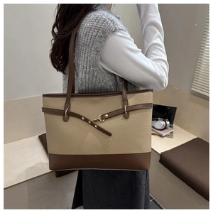 Close-up of khaki and brown patchwork leather tote bag with metallic buckle detail