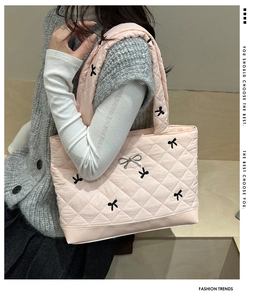 Detail of pink quilted tote bag featuring black bow embroidery and silver metal bow clasp