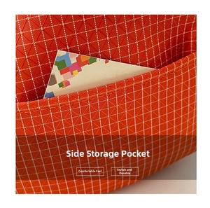 Vue détaillée de la poche latérale sur un sac bandoulière orange à motif à carreaux