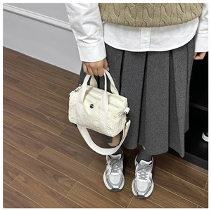 Detail of a pleated white nylon barrel bag featuring a ripple texture and wide shoulder strap