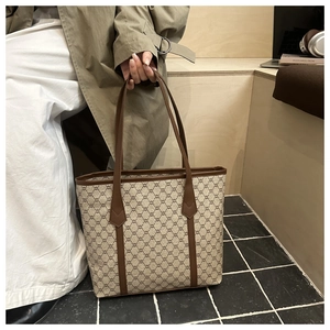 Detail of the vintage monogram tote bag with brown leather straps in a lifestyle office setting