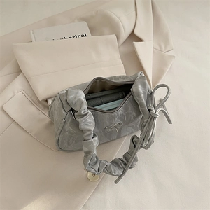 Silver crinkled leather hobo bag with bow detail and ruched handle on blazer background