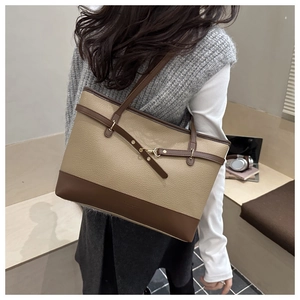 Detail of color-block tote bag featuring lychee texture and gold buckle accents