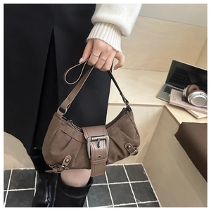 Detail der braunen Baguette-Tasche mit großer Metallschnalle und Falten-Design auf Stufen