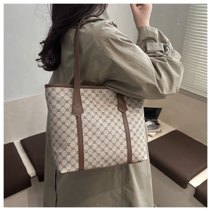 Detail view of large beige tote bag with vintage print and brown leather shoulder straps