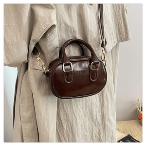 Detail view of mini dark brown bowling bag with top handles and logo embossing