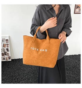 Detail of camel suede tote bag with white TOTE BAG text print and matching top handles
