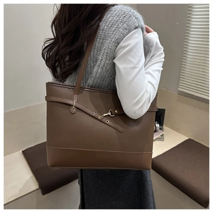 Detail of brown lychee leather tote bag with gold buckle on a model for daily commute
