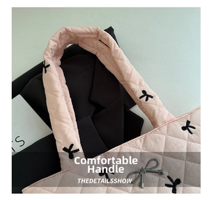 Macro view of light pink quilted tote bag with black bow embroidery and silver charm