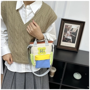 Detail of multi-color canvas crossbody bag featuring 3D pixelated H block and side pockets