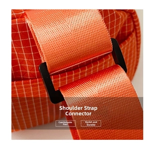 Détail de la boucle noire en D et du tissu en nylon à carreaux orange sur le sac bandoulière