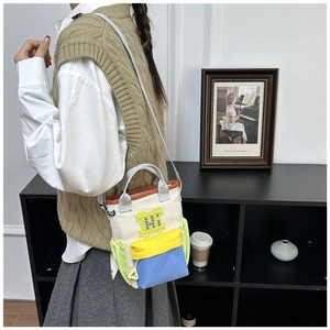 Detail of color-block canvas crossbody bag with pixel-style M letter shown on model