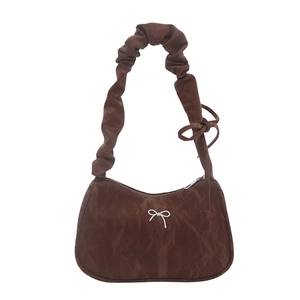 Sac à bandoulière froncé marron foncé avec nœud argenté et poignée plissée sur fond blanc