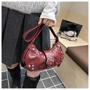 Detail view of burgundy faux leather handbag with metal buckle and rivets in Y2K style