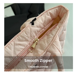 Close-up of golden metal zipper and pink quilted pattern on high-quality tote bag