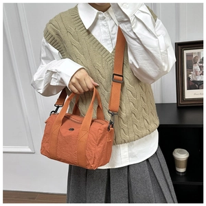 Caramel orange nylon crossbody bag with adjustable wide strap shown on a model