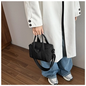 Detail of black nylon barrel crossbody bag with wide strap and metallic logo