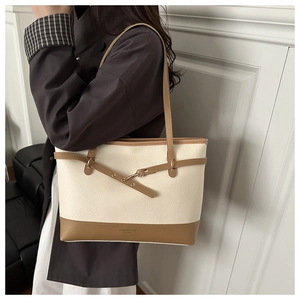 Close-up of contrast tote bag with beige lychee texture and brown strap on model shoulder