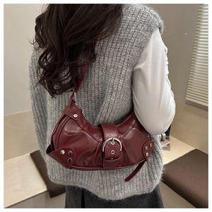 Detail of burgundy ruched crescent bag featuring a metallic buckle and vintage rivet studs