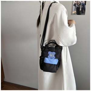 Side view of a black nylon crossbody water bottle bag with pixelated blue H logo