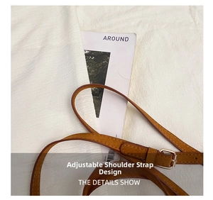 Detail of adjustable leather shoulder strap with silver metal buckle on brown handbag