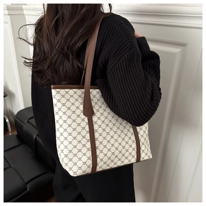 Close-up of beige canvas tote bag featuring brown vintage patterns and leather handles