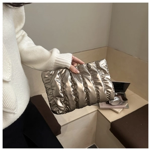 Detailaufnahme der gesteppten Puffer-Clutch in glänzendem Metallic-Champagnergold