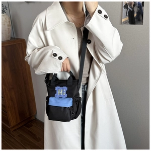 Macro detail of black canvas crossbody bag with pixel art patch and blue zipper pocket