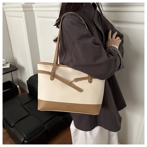 Detail of contrast stitch tote bag featuring a decorative cross strap and pebble texture
