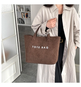 Detail of dark brown suede tote bag with white TOTE BAG text print and dual handles