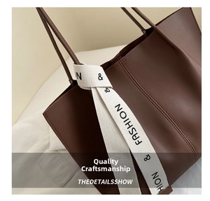 Dettaglio della borsa tote in pelle marrone scuro con tracolla bianca e cuciture rifinite