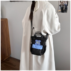 Detail of black mini tote bag with blue pixel patch and adjustable crossbody strap