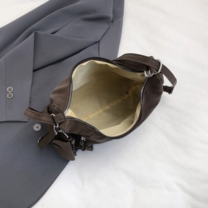 Brown lychee pattern shoulder bag with zipper closure and adjustable strap shown on a suit