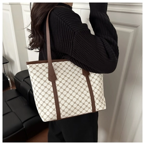 Classic monogram tote bag in canvas with brown leather trim shown on model's shoulder
