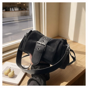Macro shot of black pleated leather shoulder bag with wide metal buckle on wooden ledge